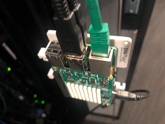 Raspberry Pi board with Ethernet cable connected, mounted at the back of a server rack